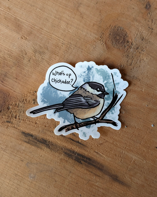 “What’s up chickadee?” vinyl sticker shown in a flat lay on a wooden surface.