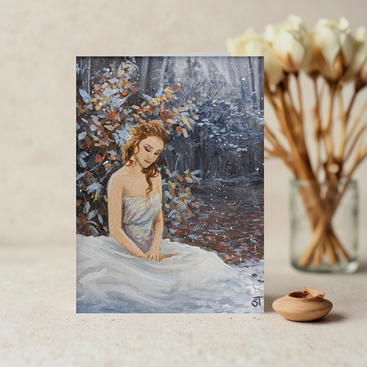 A greeting card featuring an artistic depiction of a girl in a flowing dress sitting in a forest during autumn, with a background of trees with brown leaves and a light dusting of frost.