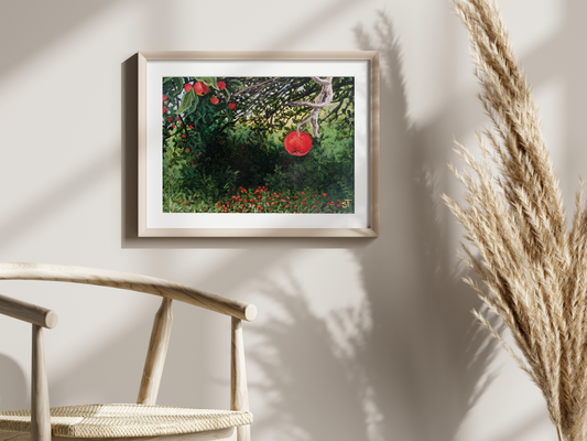 A framed art print featuring a vibrant acrylic painting of a wild apple tree with red apples, displayed on a wall above a wicker chair with a plant in the foreground.