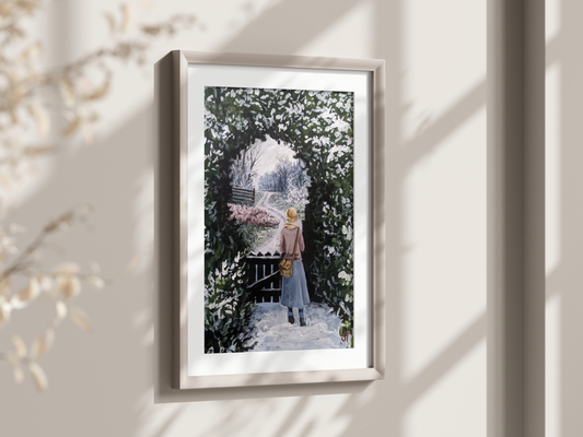 A framed art print featuring a winter scene with a young girl walking through a gate, surrounded by snow-covered evergreens and frost-covered ground, displayed on a wall in a room with natural lighting.
