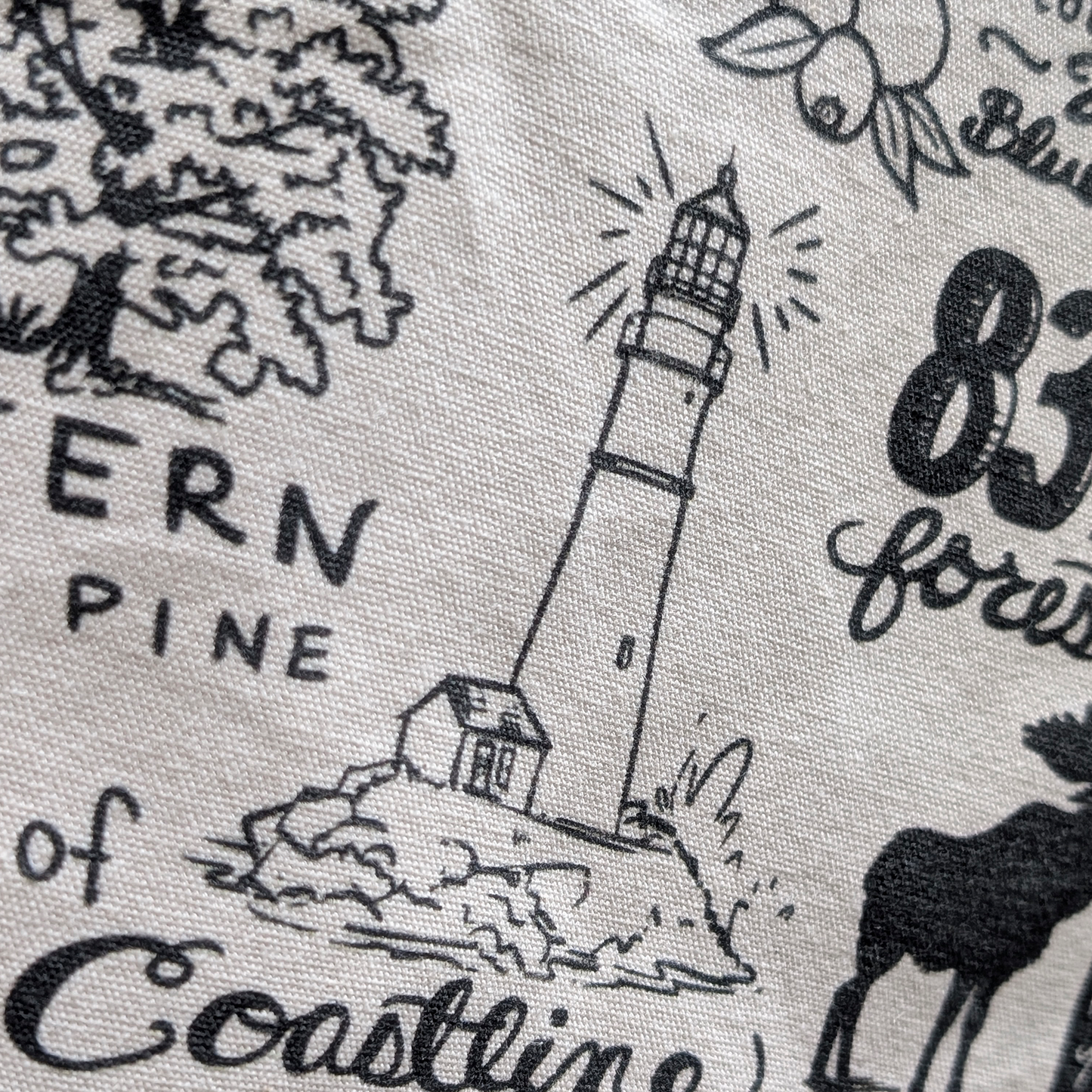 Detail view of lighthouse illustration and coastal elements on the Maine-themed eco-friendly tote bag.