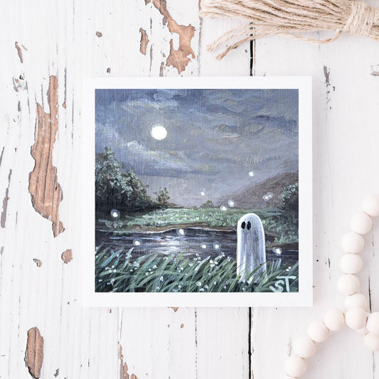 Note card showing artwork of a ghost by a river under a moonlit sky on a distressed white wooden surface.