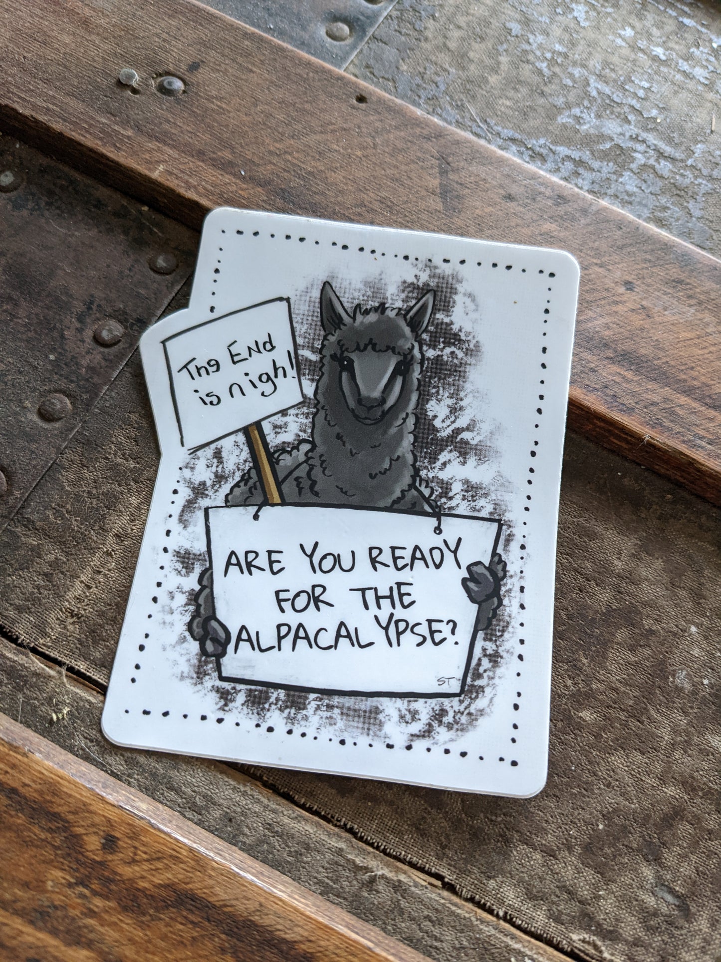 Vinyl sticker featuring a dark illustrated alpaca holding a sign that reads “Are you ready for the alpacalypse?” with a smaller sign reading “The end is nigh.”