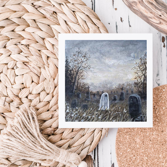 A note card featuring an artistic depiction of a ghost in a cemetery, displayed on a textured surface